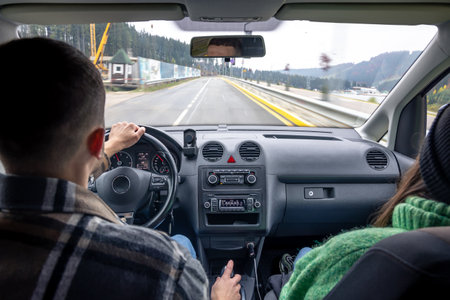 Rear back view from passenger seat of man and lady sitting inside car.の写真素材