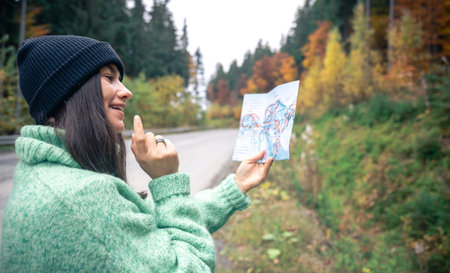 A young woman with a road map in the forest in the mountains.
