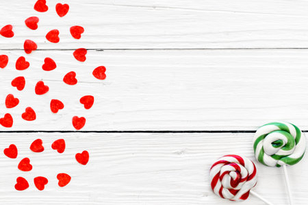Small hearts and candies on a stick on a white wooden background, flat lay.の写真素材