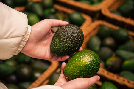 A woman chooses an avocado in a grocery store.の写真素材