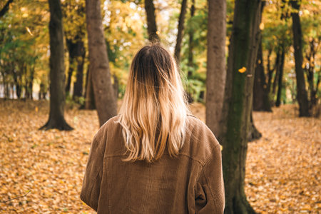A young woman with dyed hair in the autumn forest, view from the back.の写真素材