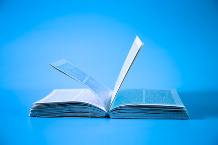 An open book on a blue background, isolated, close-up.の写真素材