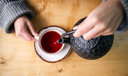 Woman in a cafe pour tea from a black cast iron teapot, top view.の写真素材