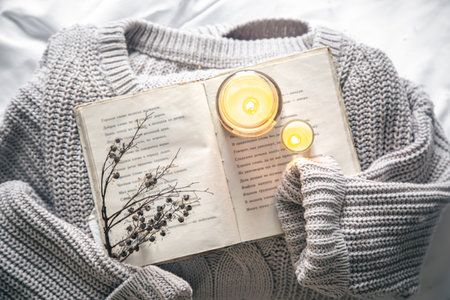 Cozy composition with a book, a knitted element and candles, top view.の写真素材