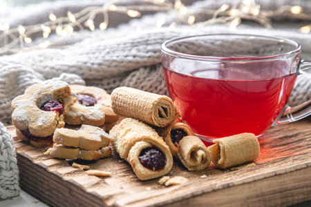 A cup of red tea and cookies on a blurred background with a knitted element.の写真素材