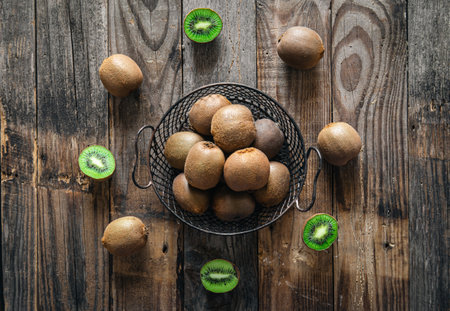 Kiwi fruit in a basket and scattered on a wooden background, flat lay.の写真素材