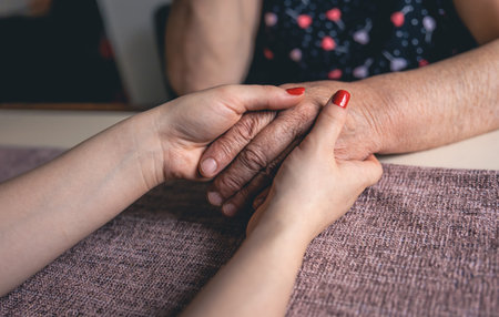 Old and young female hands are holding, elderly care and respect, close-up.の写真素材
