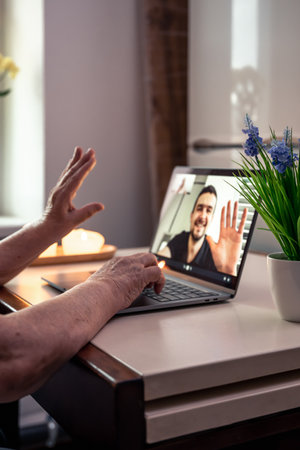 A retired woman communicates with her son via video link, uses a laptop for communication at home.の写真素材