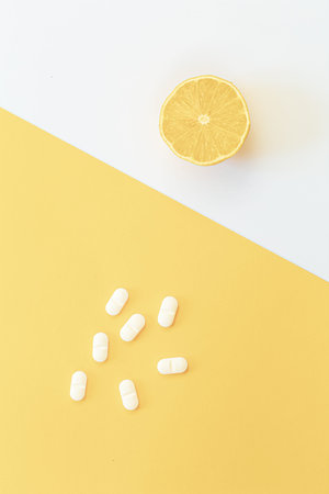 Pills and lemon on yellow background, flat lay, vitamin C concept.