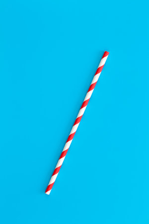 Close up of drinking straw for party, red spiral. Top view of colorful disposable eco-friendly straw for summer cocktails. Paper cocktail colorful straw isolated on blue background, isolated.の写真素材