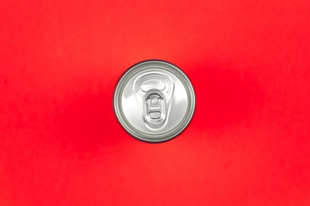 Aluminum drink or beverage can with pull ring on a red background, flat lay, copy space.
