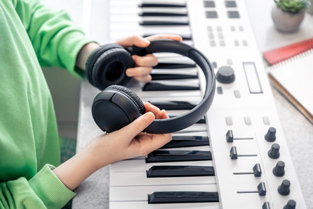Close-up, black headphones in the hands of a child on the background of the piano.の写真素材