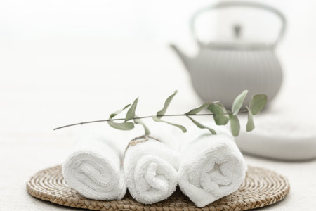 Spa composition with white towels and a sprig of eucalyptus on a blurred background.の写真素材