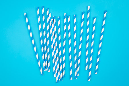 Drinking straws for party on blue background. Top view of blue paper disposable, eco-friendly straws for summer cocktails, copy space.の写真素材