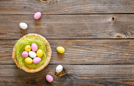Easter eggs in a decorative nest on a wooden background, top view, copy space, rustic style.