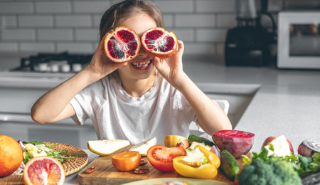 Cheerful little girl with oranges in the kitchen interior.の写真素材