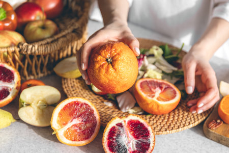 Oranges in female hands on the kitchen table, close-up.の写真素材