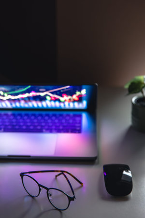 Laptop with graphs and statistics and glasses on the table.