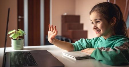 Cheerful little girl in front of laptop screen, chatting online.の写真素材