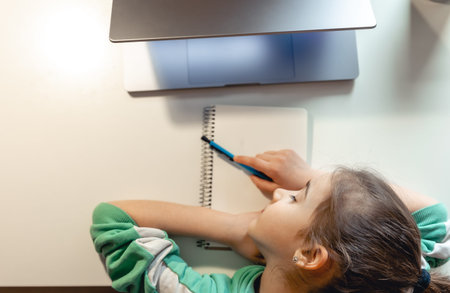 Little girl sleeps in front of a laptop on the table.