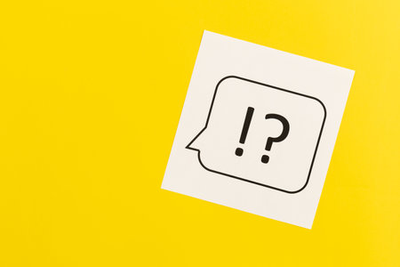 Question mark and exclamation mark on yellow background, flat lay.の写真素材