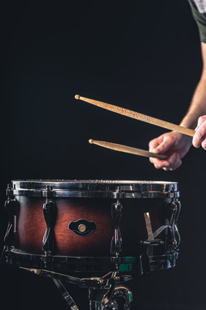 A man plays the snare drum against a dark background.の写真素材