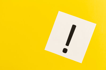 Exclamation mark on white paper on yellow background, flat lay.の写真素材