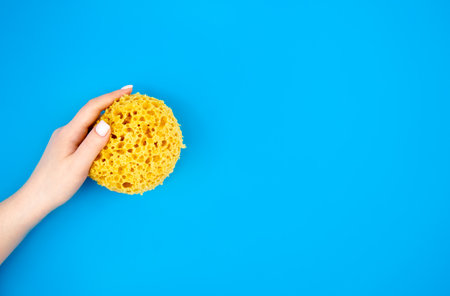 Washcloth for a shower in female hands on a blue background, flat lay.の写真素材