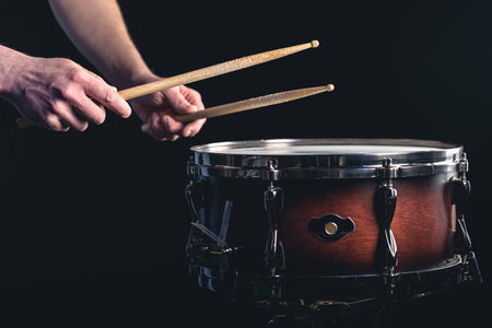 A man plays the snare drum against a dark background.の写真素材