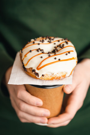 A cup of coffee and a donut in male hands, close-up.の写真素材