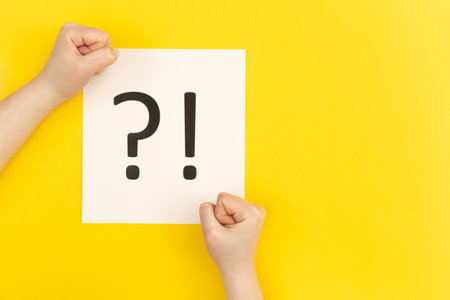 Question mark and exclamation mark on yellow background, flat lay.の写真素材
