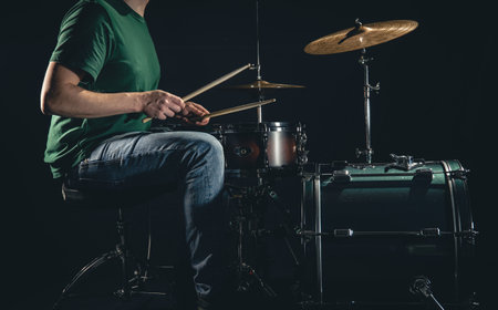 A man plays a drum kit on a black background.の写真素材