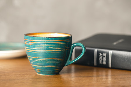 A cup of coffee and a Bible on a wooden table, close-up.の写真素材