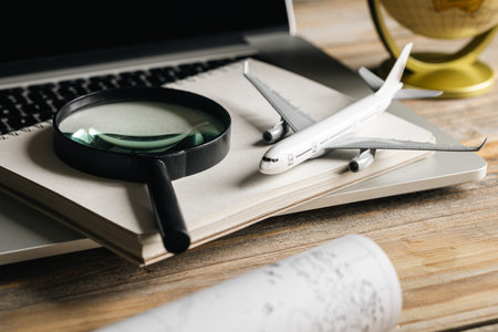 Travel composition with airplane, magnifying glass and map on a wooden table.の写真素材