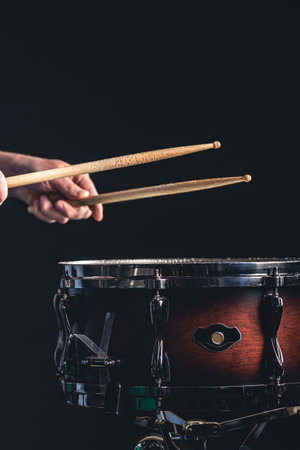 A man plays the snare drum against a dark background.の写真素材