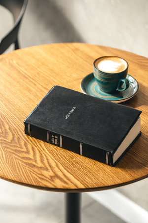 A cup of coffee and a Bible on a wooden table, close-up.の写真素材