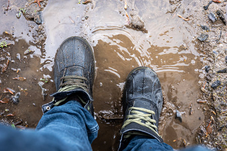 View from above on pair of trekking shoes in a mud.の写真素材