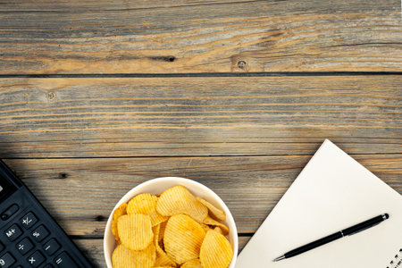 A plate of potato chips, a calculator and a notebook, top view.の写真素材
