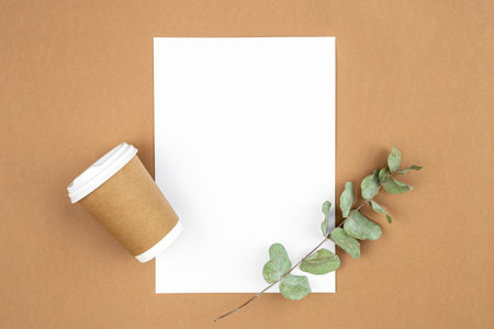 Craft paper coffee cup and eucalyptus sprig on eco background, flat lay.の写真素材