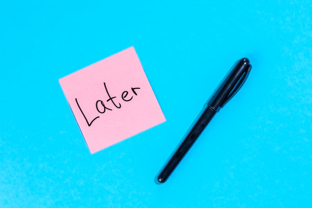 Pink note with with inscription Later and marker on blue background, flat lay.の写真素材