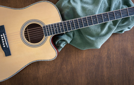 Guitar and plaid on a wooden background, top view.