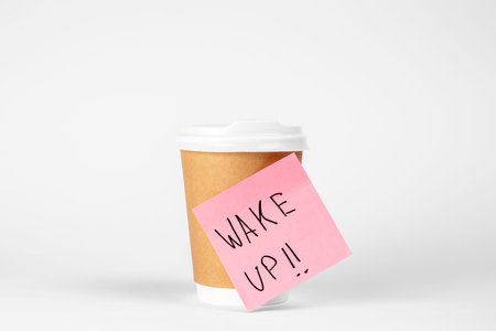 Disposable paper cup with a reminder paper on a white background isolated.の写真素材