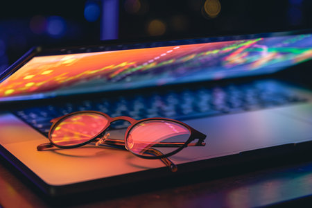 Close up of laptop keyboard colorful neon illumination and eyeglasses.の写真素材