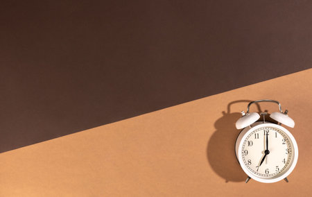 White alarm clock on a brown background, top view.