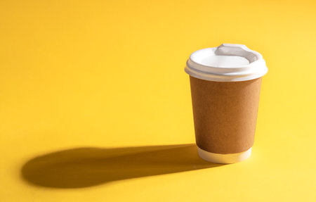 Disposable paper cup on a yellow background, close-up.の写真素材