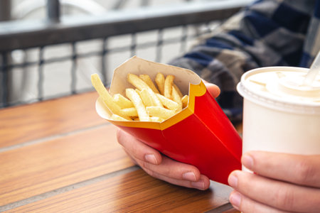 Close-up, french fries and a drink in male hands.の写真素材