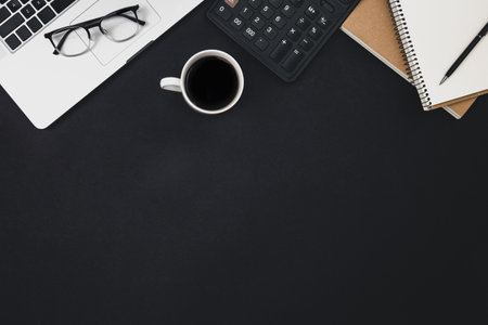 Flat lay black background with laptop, coffee cup and calculator, top view.の写真素材