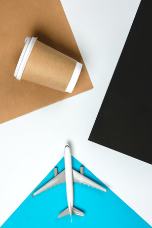 Paper cup and airplane model on colored paper background, top view.の写真素材