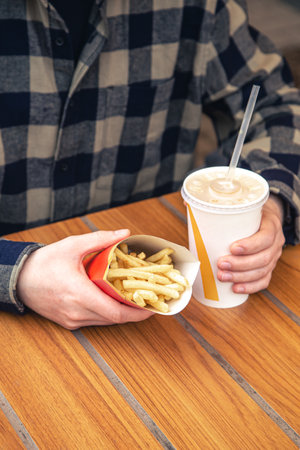 Close-up, french fries and a drink in male hands.の写真素材