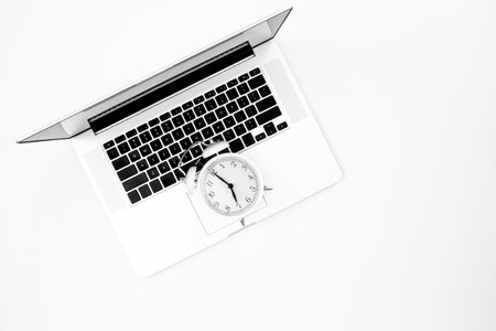 Alarm clock and a laptop on a white background, top view.の写真素材
